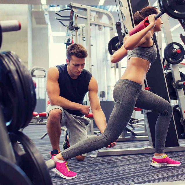 Gym Instructor Helping A Lady Lifting Weights | Northeast Health and Fitness in Quincy, MA